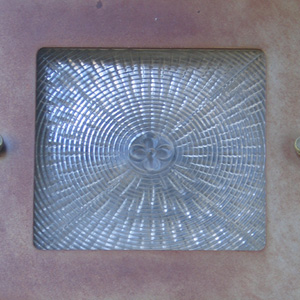 Molded flower in glass light cover, on the west side entrance